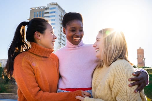 Three female friends affectionately hug each other having fun together laughing happy smiling. Collective lovely embrace concept.