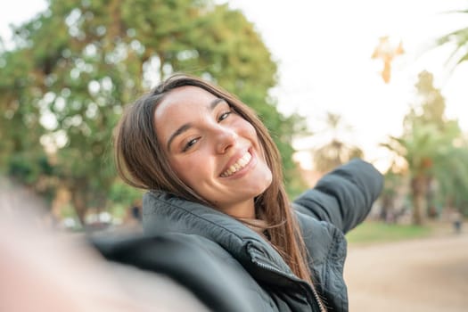 Influencer woman making a selfie blog outdoors in the park. Happy smiling lady student taking video call. Technology, education, Erasmus and communication concept. High quality photo