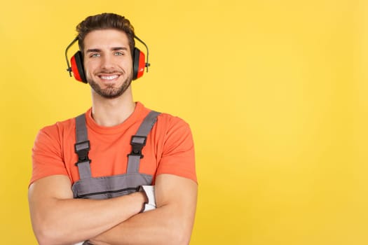 Friendly caucasian man carpentry worker in work uniform in studio with yellow background