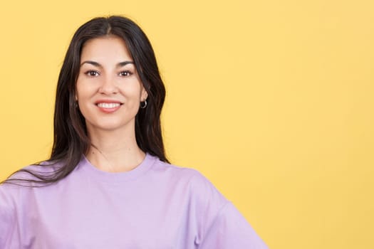 Happy woman looking at the camera relaxed in studio with yellow background