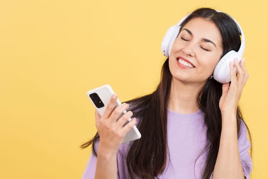 Caucasian woman listening to music with the eyes closed in studio with yellow background