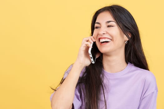 Happy caucasian woman talking to the mobile in studio with yellow background