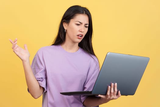 Caucasian woman having a problem with a laptop in studio with yellow background