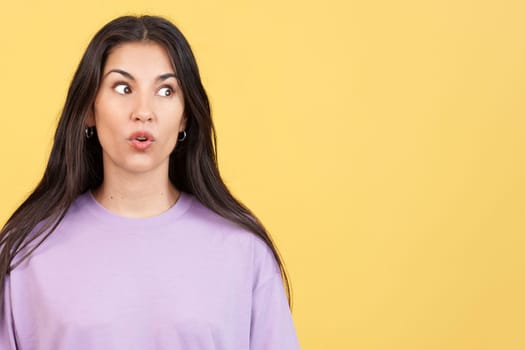 Surprised caucasian woman looking away in studio with yellow background