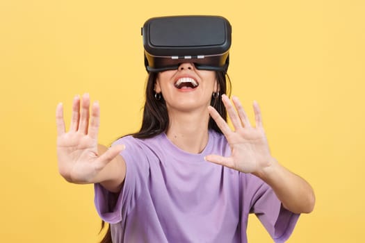 Happy caucasian woman with Virtual Reality goggles in studio with yellow background