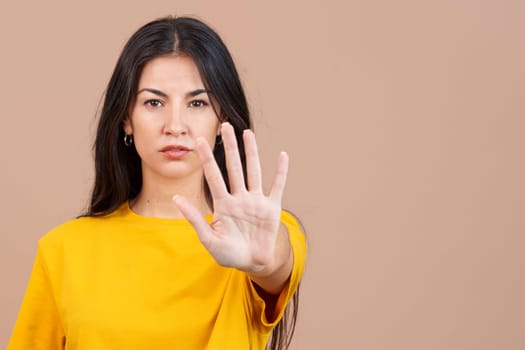 Caucasian woman gesturing prohibition with hand in studio with brown background