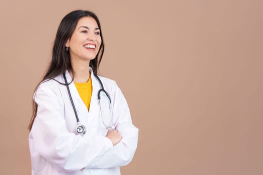 Friendly caucasian female doctor in uniform and stethoscope in studio with brown background