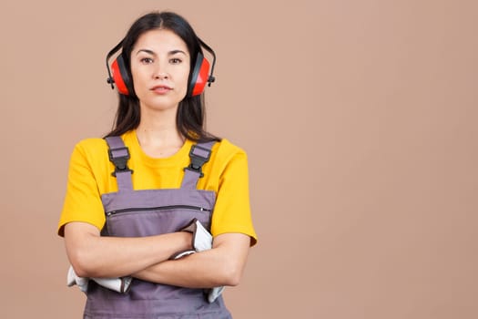 Serious female worker standing with arms crossed looking at camera. Brown background