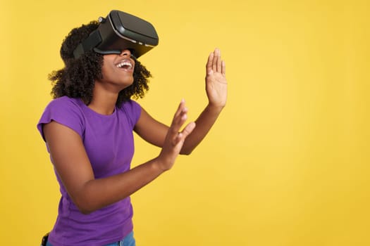 Curious woman gesturing while wearing a virtual reality goggles in studio with yellow background