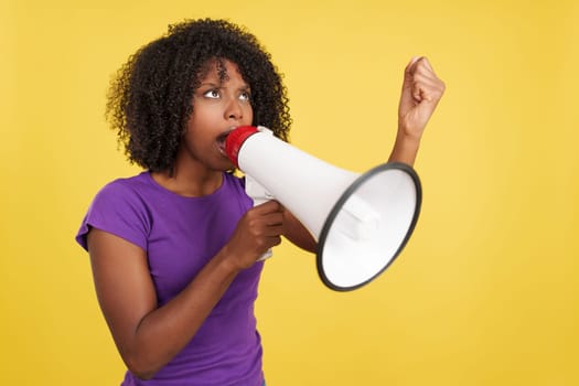African woman yelling while using a mefaphone in studio with yellow background