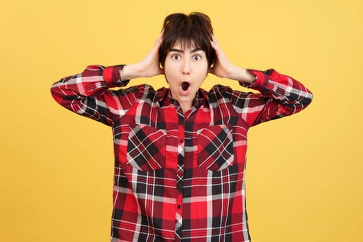Cool Androgynous person looking at camera while expressing surprise in studio with yellow background