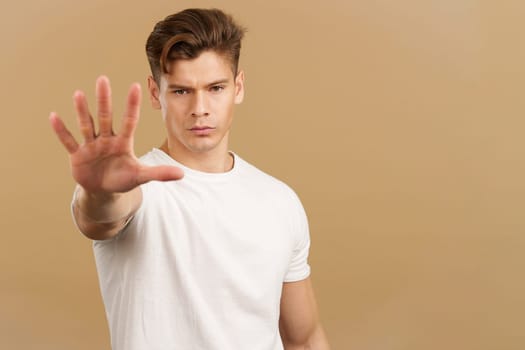 Handsome man gesturing stop with the palm of the hand in studio with brown background