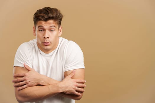 Man looking at camera woman gesturing he is cold in studio with brown background