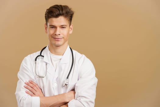 Handsome doctor looking at camera with arms crossed in studio with brown background