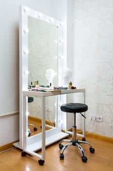 Vertical photo of the dressing room of a backstage with make up tools and a chair