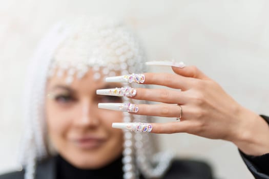 Focus on a white and long fake nails of an artist