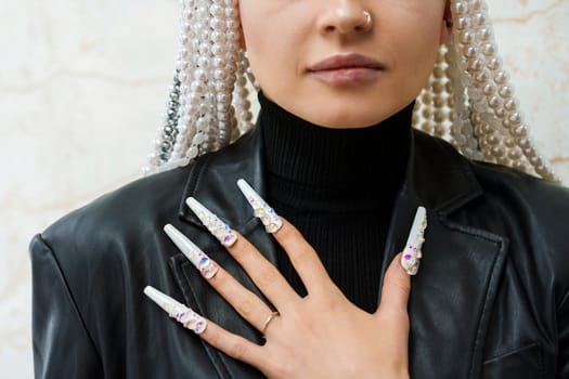 Cropped photo of a female artist showing long and decorated fake nails