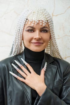 Vertical portrait of a female artist showing a hand with decorated fake nails