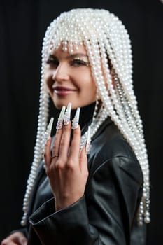 Studio portrait of a woman with fantasy make up with nail extensions and a wig of pearls