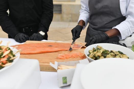 Cooks cut salmon fish at a wedding