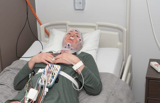 Middle aged woman measuring brain waves, examining polysomnography in sleep laboratory, High quality photo