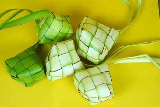 Ketupat or woven palm leaves for rice cakes to celebrate Eid Mubarak in Indonesia. Isolated on yellow background.