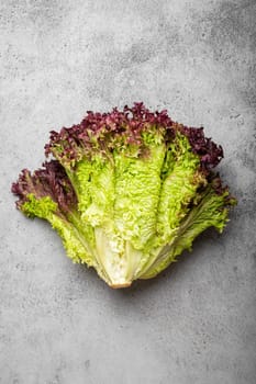 Fresh raw organic farm Lolo Rosso lettuce salad on grey rustic stone background top view, healthy green salad in balanced nutrition and cooking concept