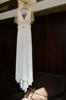 The Wedding dress hanging on a wall and golden shoes