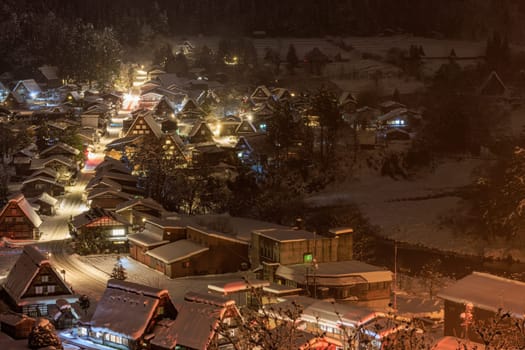 Traditional Japanese village amid trees and snow on misty winter night. High quality photo