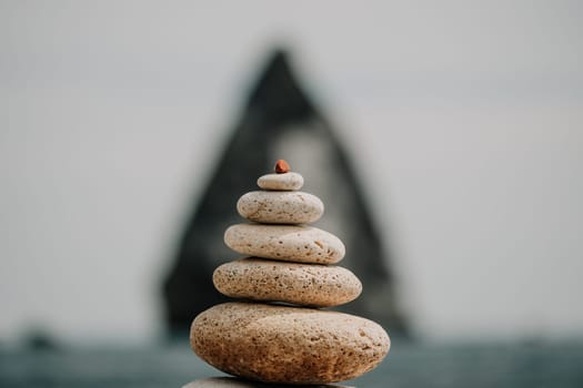 Pyramid stones on the seashore with warm sunset on the sea background. Happy holidays. Pebble beach, calm sea, travel destination. Concept of happy vacation on the sea, meditation, spa, calmness.