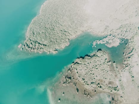 Aerial landscape from flying drone storage reservoir at mountain foot covered colorful spring forest. Beautiful view from above blue lake among highlands