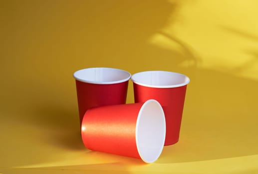 three red paper coffee cups on a yellow background is a morning concept