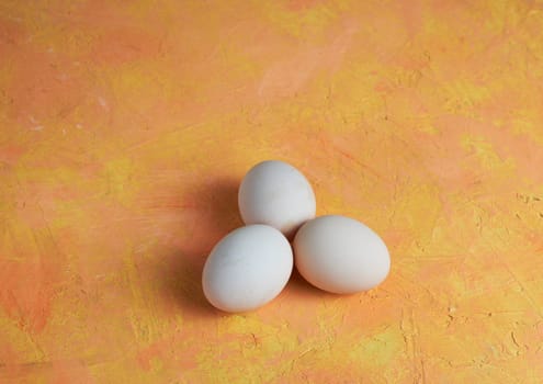 Three red Easter white eggs on a yellow background. Colorful decoration of Easter eggs. Flat position, top view. with a place to copy the text. Minimal idea for an Easter concept