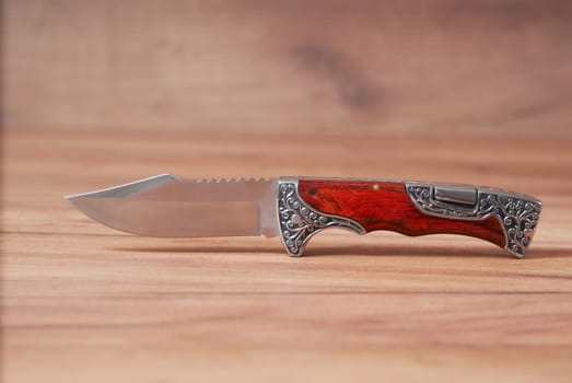 hunting knife on a wooden background with a beautiful metal pattern on the handle