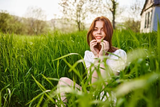 happy smiling redhead woman resting sitting in tall grass. High quality photo