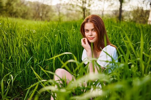 cute, contented woman sitting in tall green grass outdoors. High quality photo