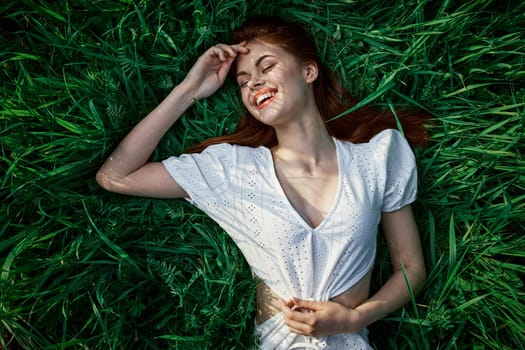 a woman in a white dress is lying on the grass in sunset. High quality photo