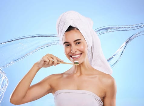 Woman, water splash and toothbrush for teeth, dental care or skincare hygiene against blue studio background. Portrait of happy female smile in tooth whitening, oral or mouth treatment for healthcare.