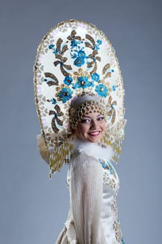 Portrait of smiling young woman in kokoshnik, on blue background