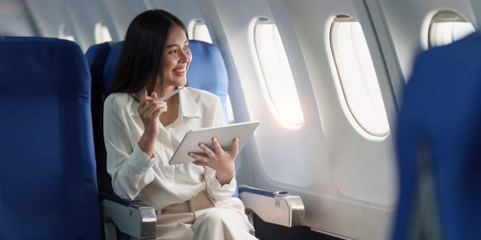 Beautiful Asian businesswoman working with digital tablet in aeroplane. working, travel, business concept.