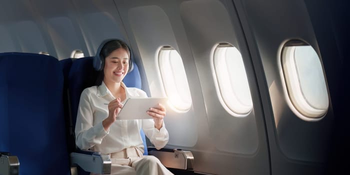 Beautiful Asian businesswoman working with digital tablet in aeroplane. working, travel, business concept.