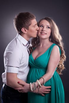Image of man kissing cheerful pregnant woman, close-up