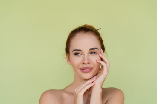 Beauty portrait of young topless red hair woman with bare shoulders on green background with perfect skin and natural makeup