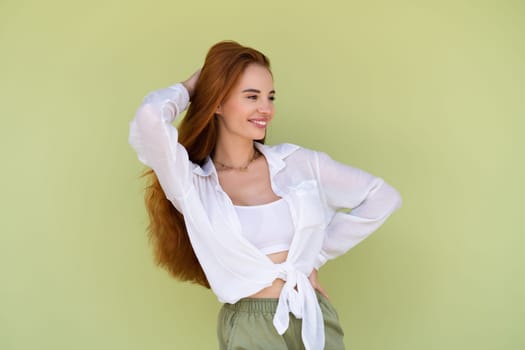 Beautiful long red hair woman in casual shirt on green background positive smiling laughing enjoying exited