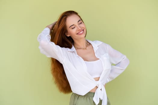 Beautiful long red hair woman in casual shirt on green background positive smiling laughing enjoying exited