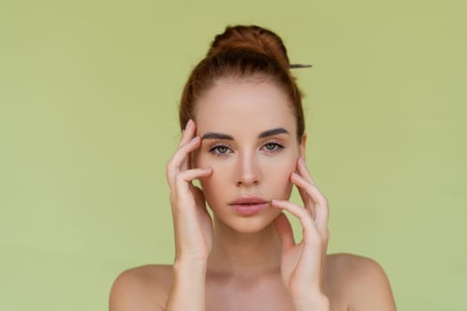 Beauty portrait of young topless red hair woman with bare shoulders on green background with perfect skin and natural makeup