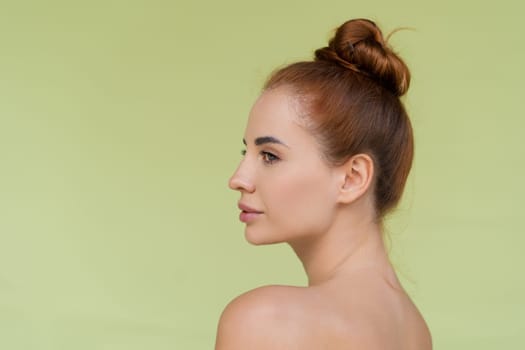 Beauty portrait of young topless red hair woman with bare shoulders on green background with perfect skin and natural makeup