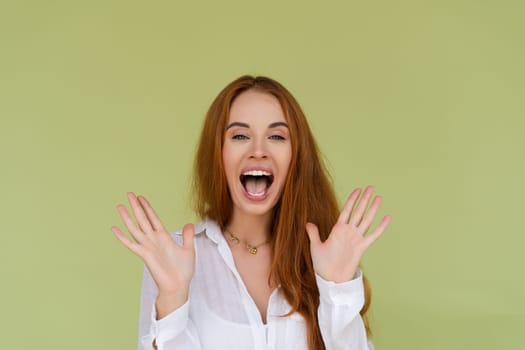 Beautiful red hair woman in casual shirt on green background happy look to camera surprised with mouth open