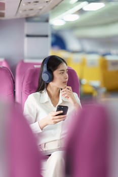 Beautiful Asian business woman listen music by mobile phone during flight in aeroplane. working, travel, business concept.