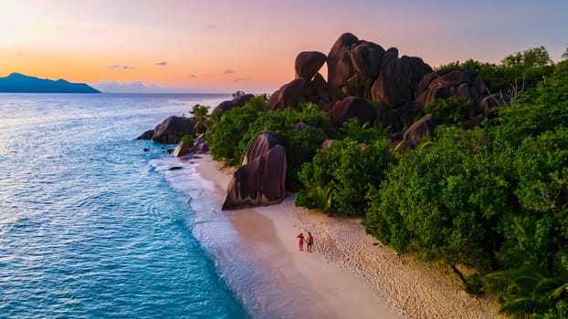 Anse Source d'Argent beach, La Digue Island, Seyshelles, Drone aerial view of La Digue Seychelles couple men and woman walking at the beach during sunset at a luxury vacation